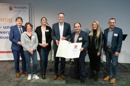 Innenminister Michael Ebling (Mitte) überreicht Ortsbürgermeister Tobias Rohrwick die Anerkennungsurkunde als Schwerpunktgemeinde der Dorferneuerung.
Mit dabei sind (v. l. n. r.) Landrat Heiko Sippel, Nicole Becker-Mutschler (Sachbearbeiterin Dorferneuerung Kreisverwaltung Alzey-Worms), Carolin Schreiber (Sachbearbeiterin Dorferneuerung VG Monsheim), Nicole Müller (stellv. Bauamtsleitung VG Monsheim) und VG-Bürgermeister Ralph Bothe.

Foto: Innenministerium RLP/Stephan Dinges